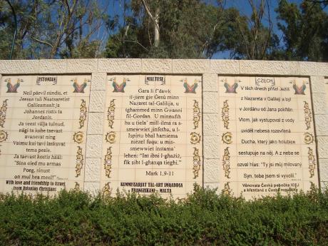 Biblické texty na zdi kolem křtitelnice v různých jazycích včetně češtiny