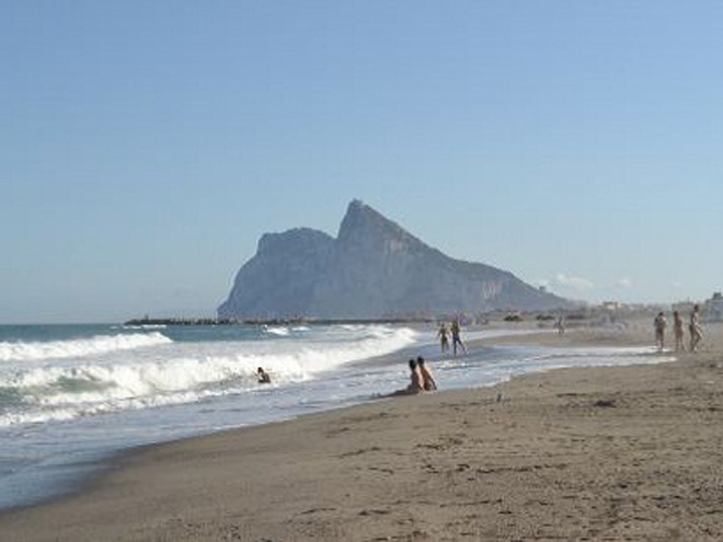 Písečná pláž se skálou Gibraltar v pozadí