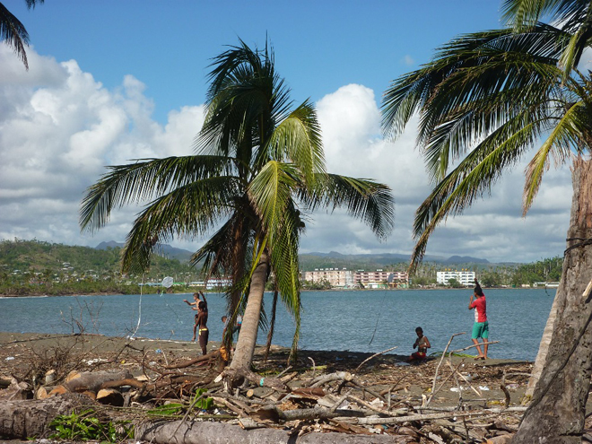Děti hrající si na pláži v Baracoa mezi polámanými palmami