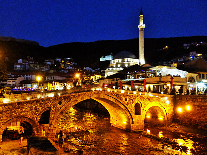 Noční Prizren s osvětleným kamenným mostem a mešitou