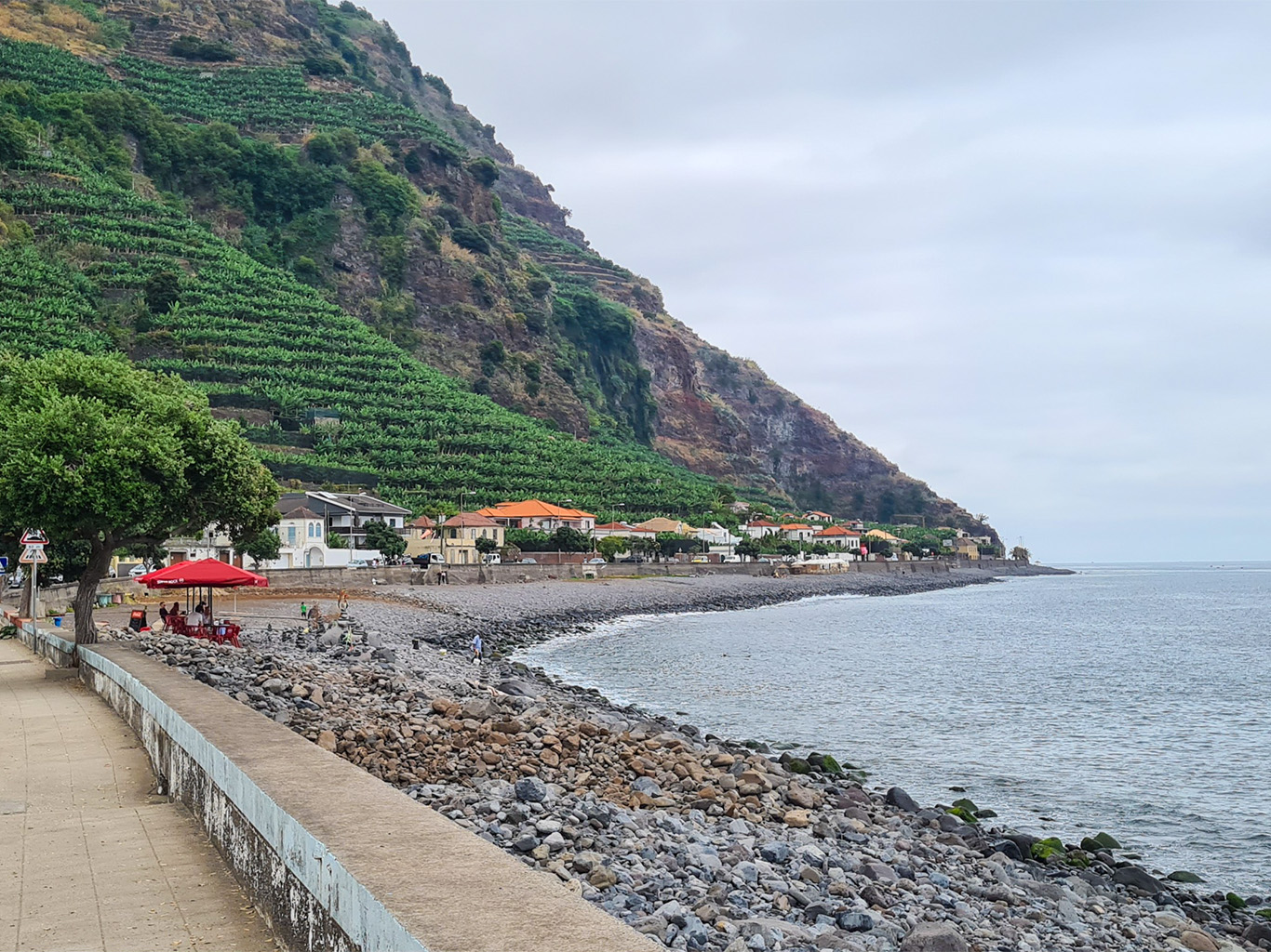 Oblázková pláž ve vesnici Madalena do Mar obklopené banánovníky