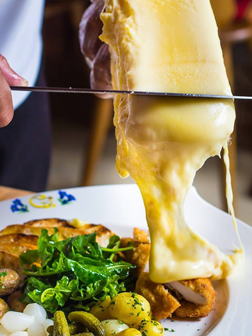 Sýr raclette se servíruje postupným seškrabáváním horní roztavené vrstvy