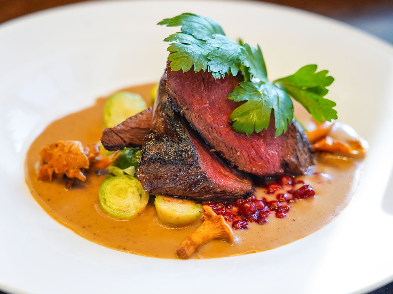 Sobí steak podávaný s vařenými bramborami a brusinkami