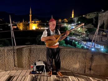 Místní si přivydělává hraním na mandolínu na Starém mostě v Mostaru