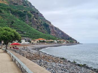 Oblázková pláž ve vesnici Madalena do Mar obklopené banánovníky