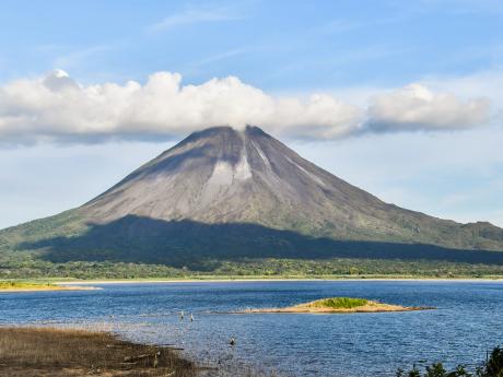 Vulkán Arenal se tyčí nad hladinou největšího kostarického jezera