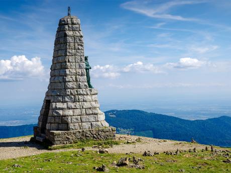 Mohyla shlížející na zalesněné zaoblené vršky pohoří Vogézy