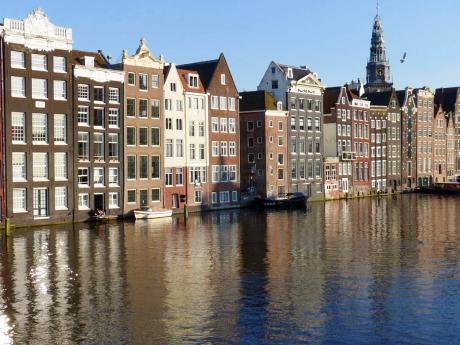 Úzké domy postavené přímo u kanálu v Amsterdamu