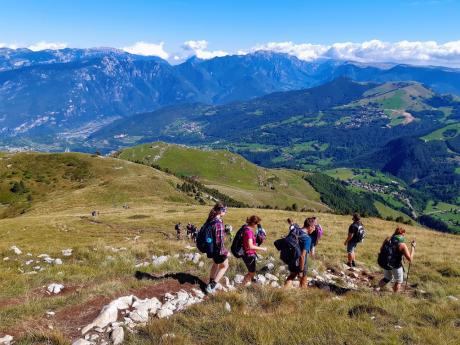 Turisté sestupují po travnatých pláních z Monte Altissimo di Nago
