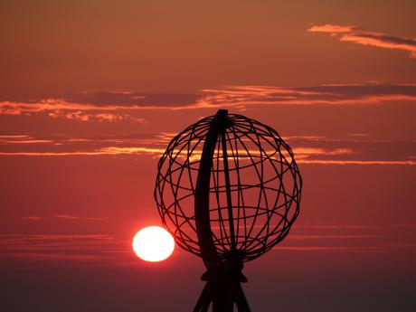 Silueta glóbusu s půlnočním sluncem na Nordkappu